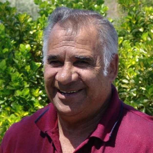 Aboriginal man in red shirt looks at camera