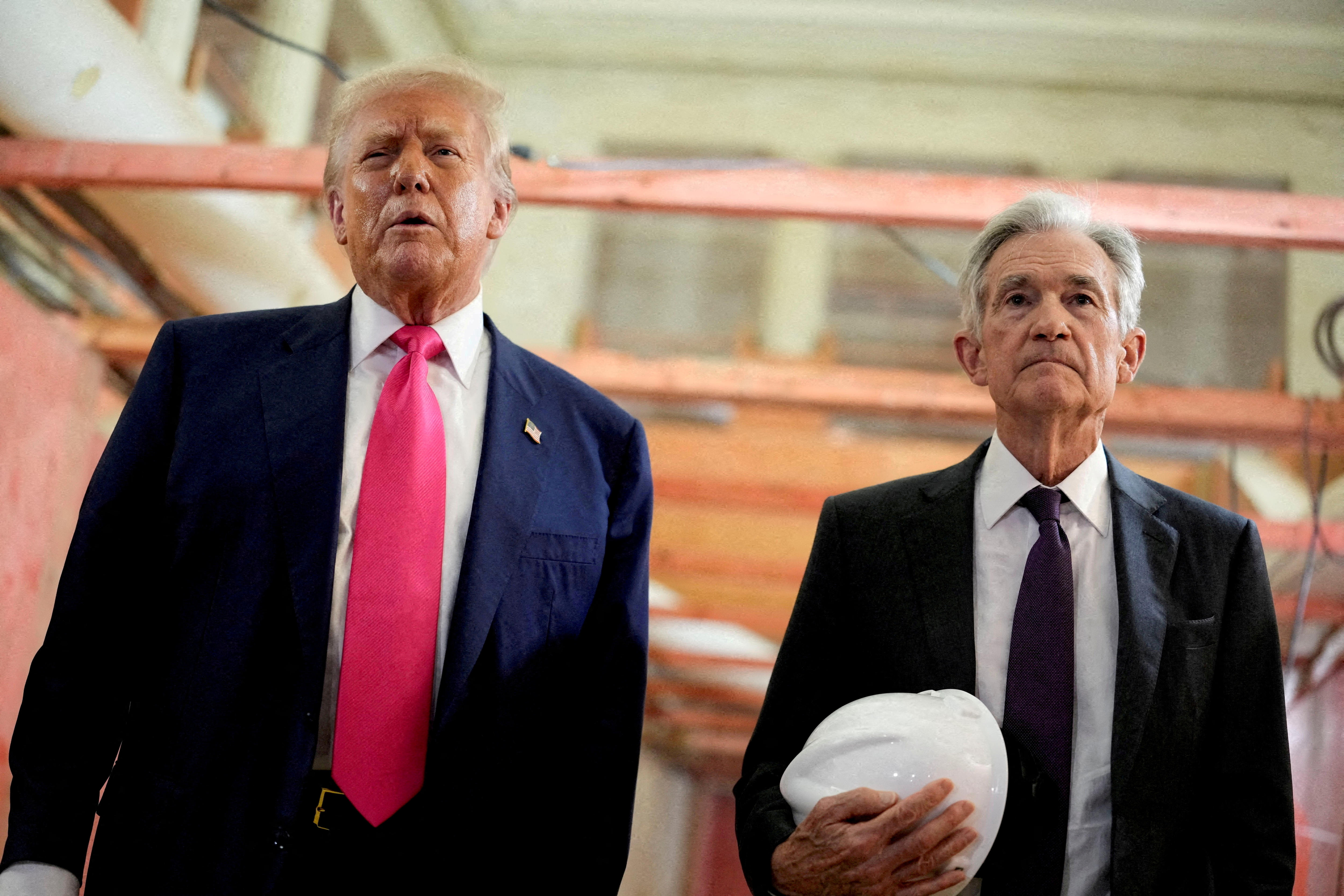Donald Trump and Jerome Powell stand side by side, with Powell holding a white hard hat.