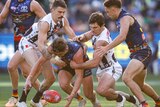 A pack of Crows and Magpies players converge around the ball