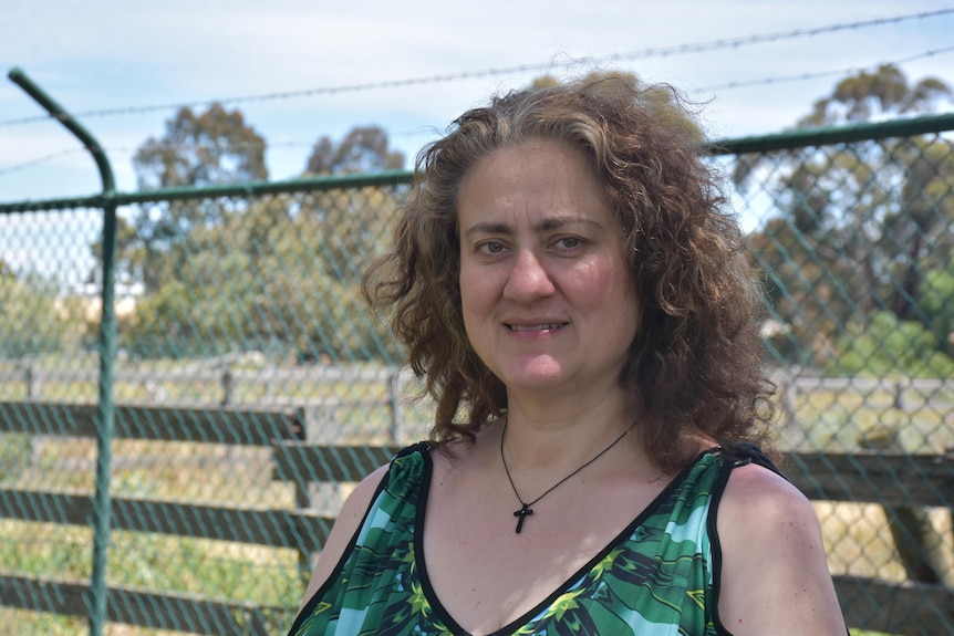 Vasso Apostolopoulos stands in front of a fenced-off paddock, smiling.