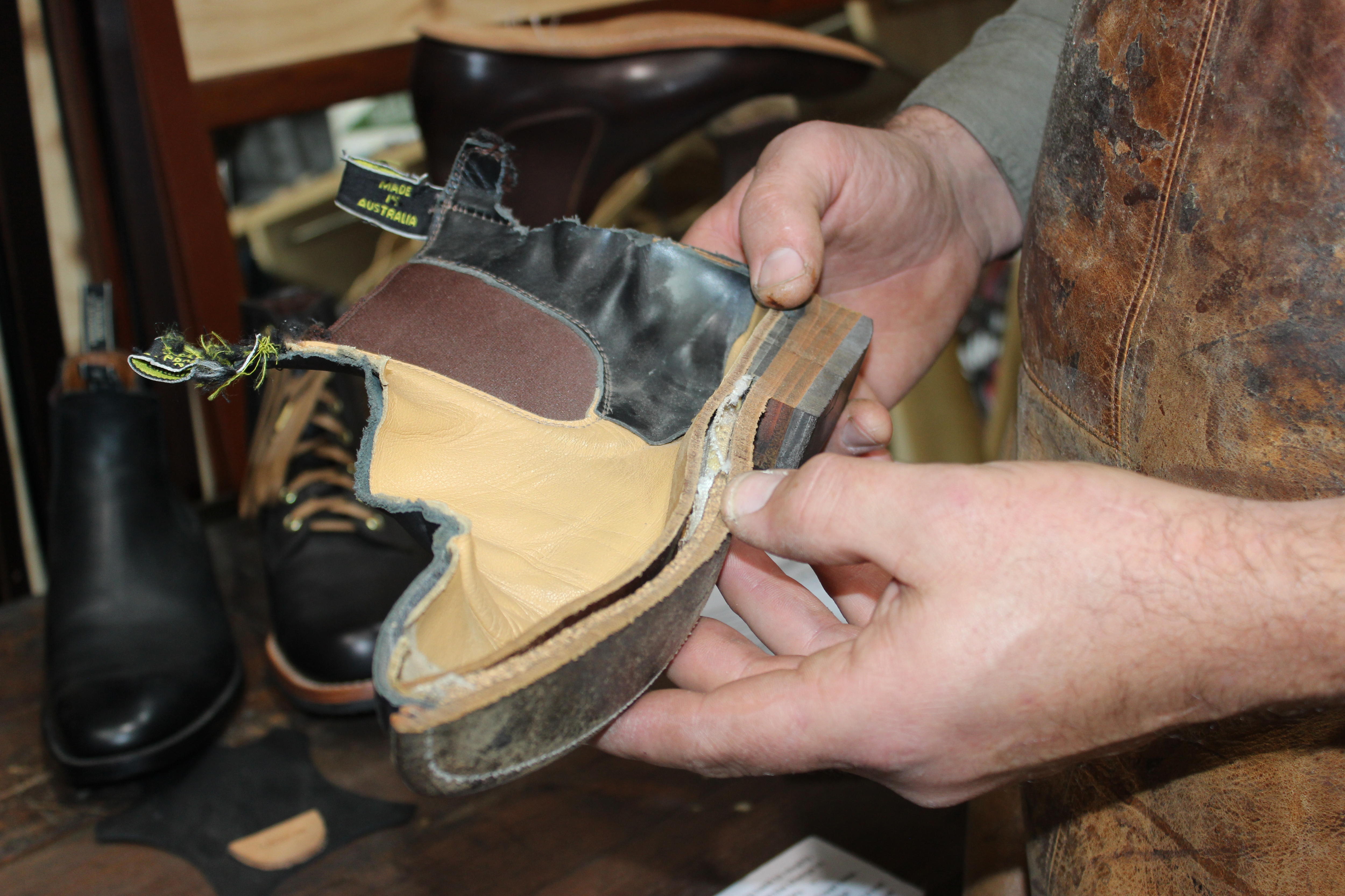 Leather craftsman Jess Wootten holds a cut-in-half leather boot.