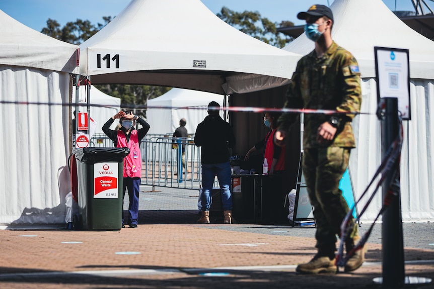 A woman in a high vis vest and a soldier at the vaccination hub