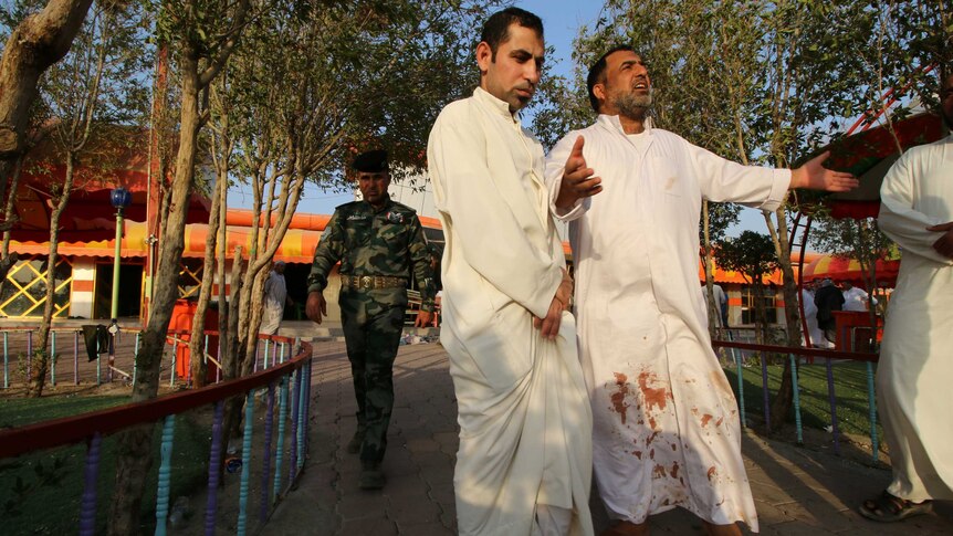 Iraqi people react at the site of a bomb attack.