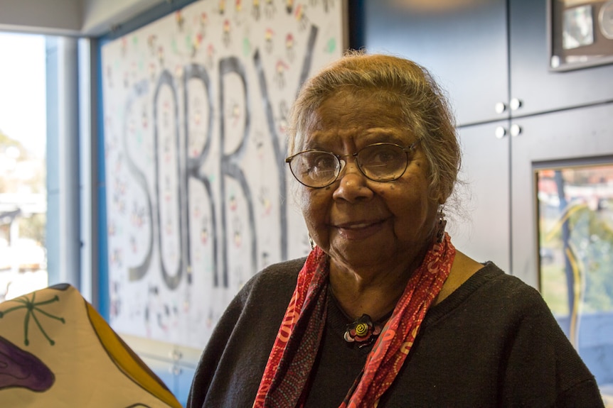 Aunty Ali golding standing in front of a Sorry sign