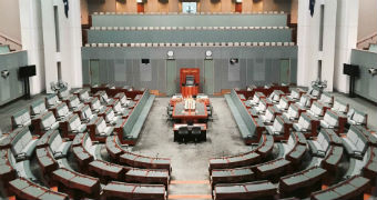 The House of Representatives, an expansive room with green carpet and chairs. There is nobody inside.