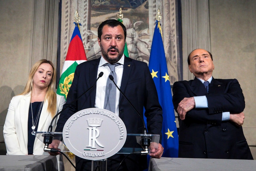 The League party's leader Matteo Salvini speaks at a conference as Silvio Berlusconi and Giorgia Meloni stand behind