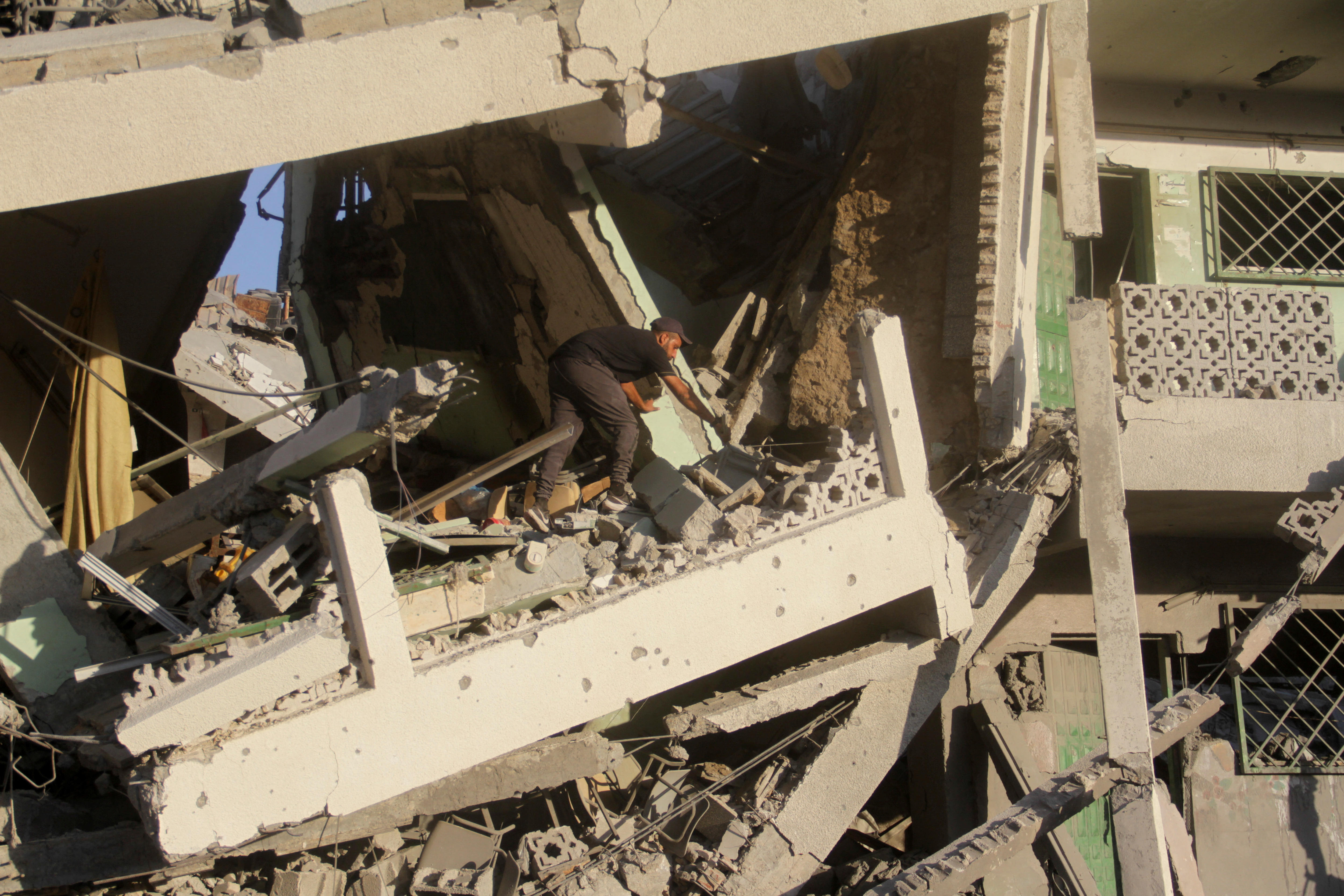 A man picks through broken concrete in a destroyed multi-level building
