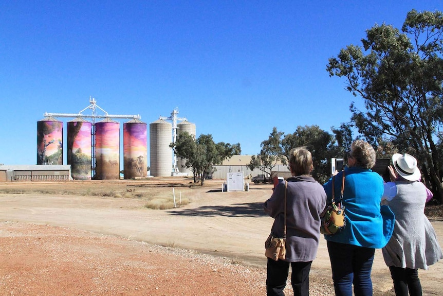 Tourists take photos of Thallon's four silos that are painted with artwork in Queensland outback town.