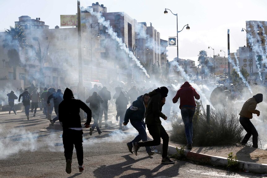 Palestinian protesters run from tear gas