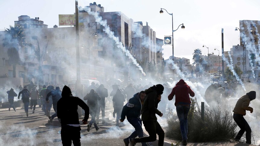 Palestinian protesters run from tear gas