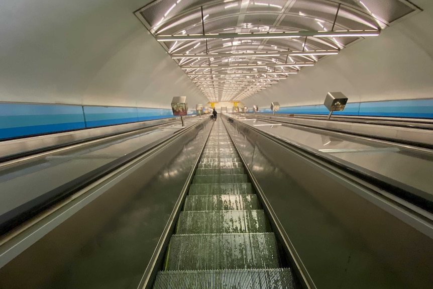 The view looking down a steep train station escalator in Melbourne.