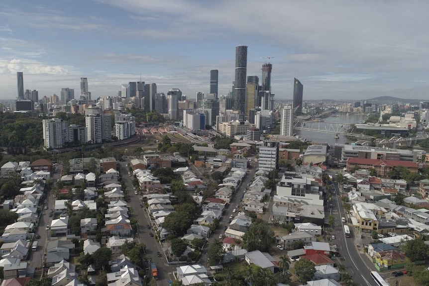 Drone aerial photo of houses in inner-city suburbs, near-empty local roads, city skyline and Brisbane river on May 1, 2020.