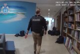 Police inside a school hallway with school bags strewn around