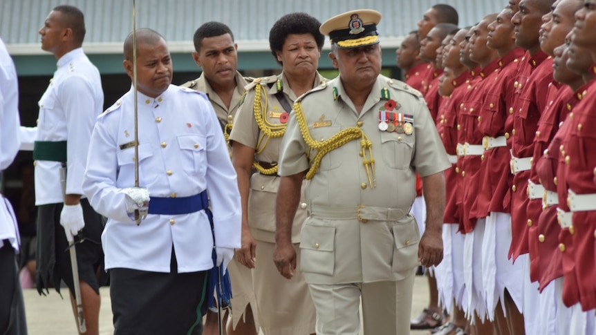 Francis Kean in khaki uniform takes a Guard of Honour with other officers in traditional Pacific clothes.