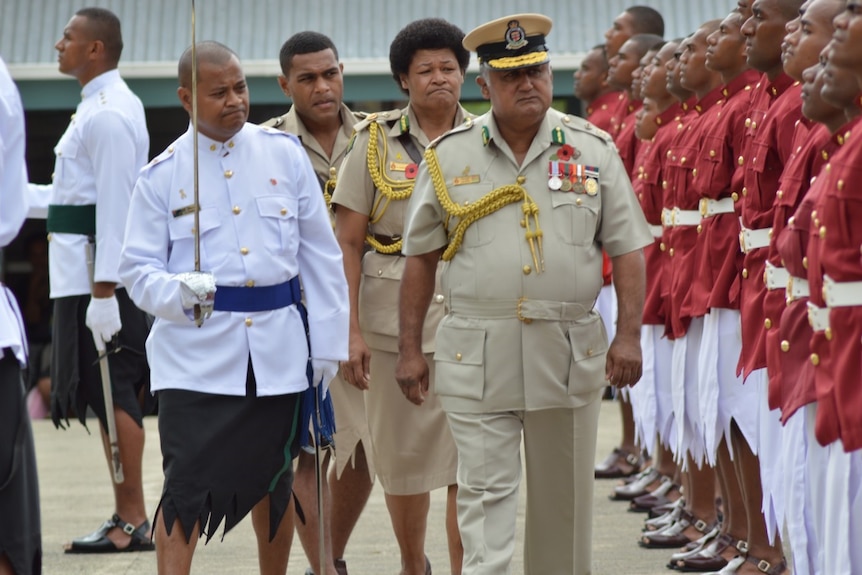 Francis Kean in khaki uniform takes a Guard of Honour with other officers in traditional Pacific clothes.