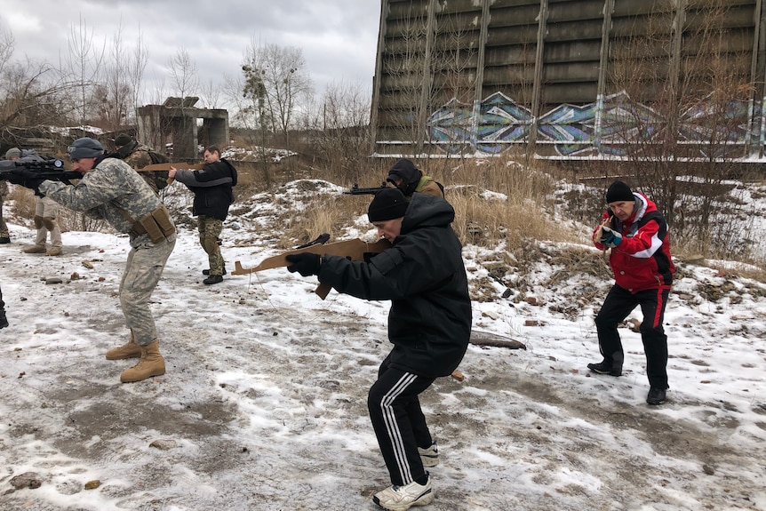 A group of men in mixed outfits go through military drills.