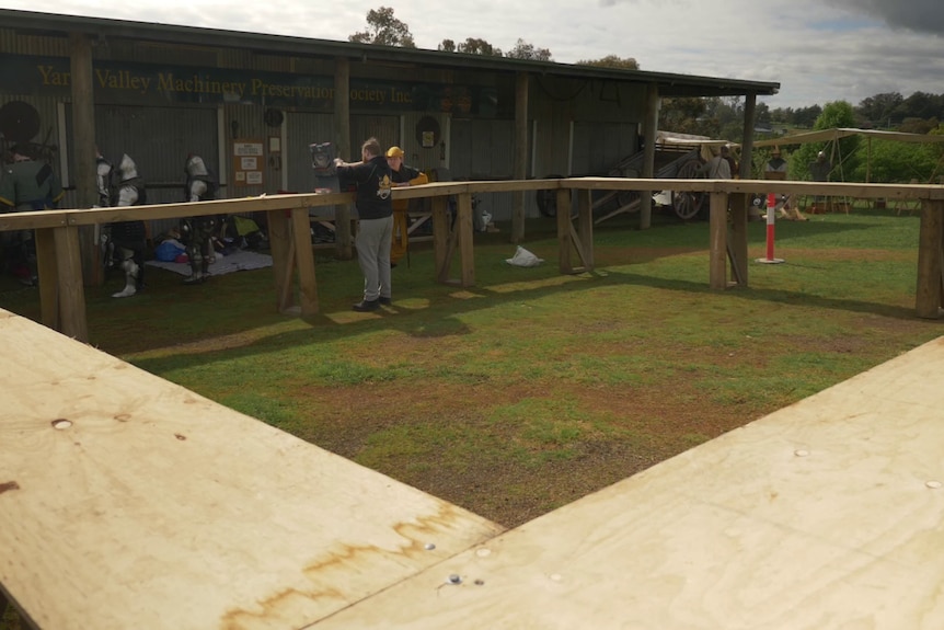 A wide shot of a Buhurt fighting arena, or a 'list', with some people setting up to fight.