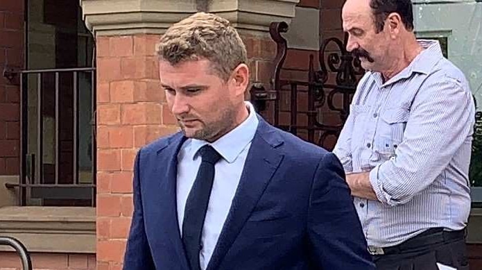 A man in a blue suit walks down steps in front of a red brick building