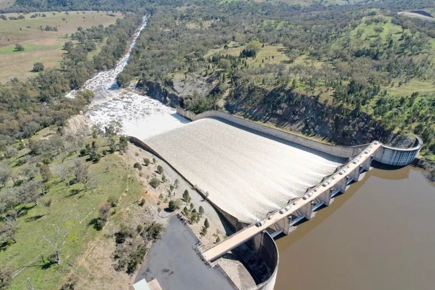 A drone image of a full dam with water being released