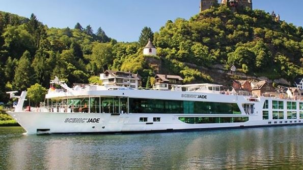 A Scenic river cruise ship in front of a castle.