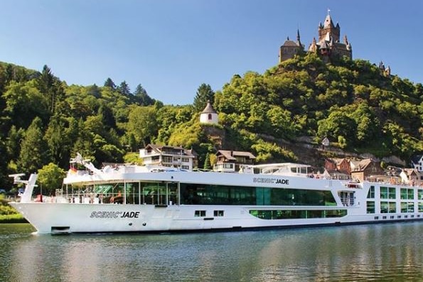 A Scenic river cruise ship in front of a castle.