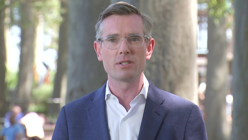 a man wearing glasses standing outdoors talking