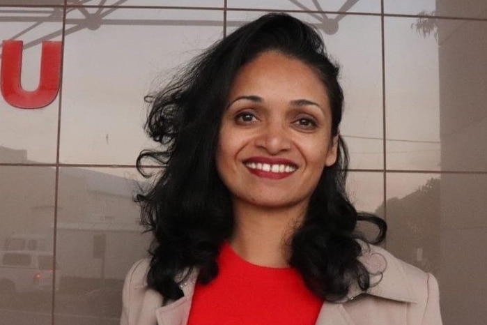 A smiling woman in a building foyer. 