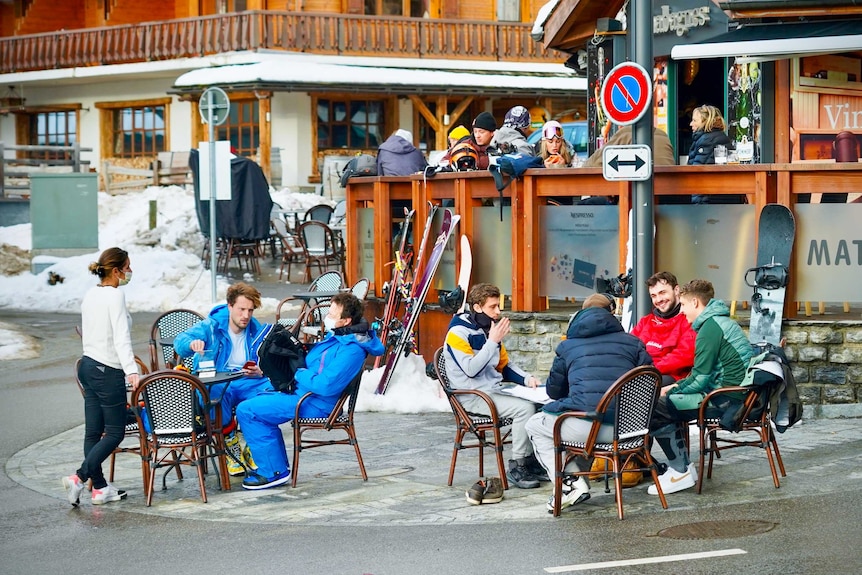 People in ski gear sitting at outdoor cafe tables