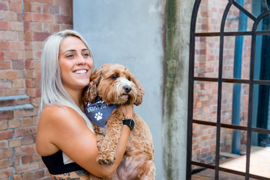 A woman holds a dog and smiles.