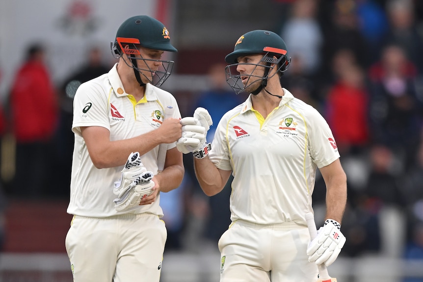 Australia batters Cameron Green and Mitch Marsh bump fists as they walk off the field during an Ashes Test at Old Trafford.
