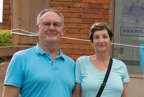 Rod and Margot Cunich standing on the steps in front of Dave Sharma's electoral office with a Quiet Australians Stand Up sign