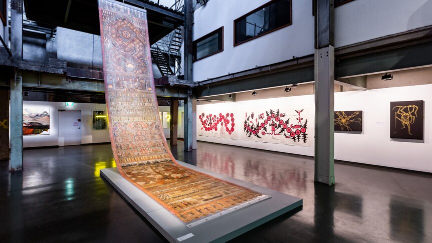 Large patterned scroll work suspended in a gallery foyer in a converted powerhouse building.