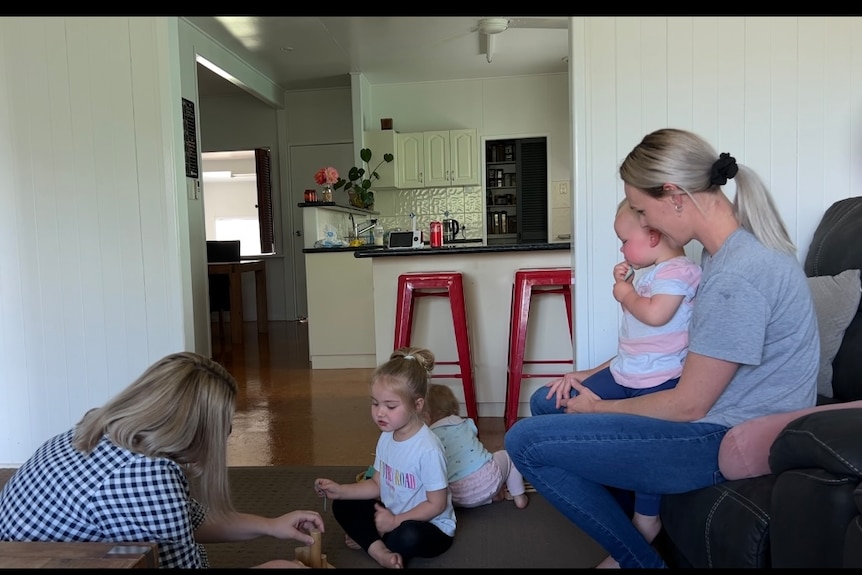 Two mothers play on the floor with their toddlers