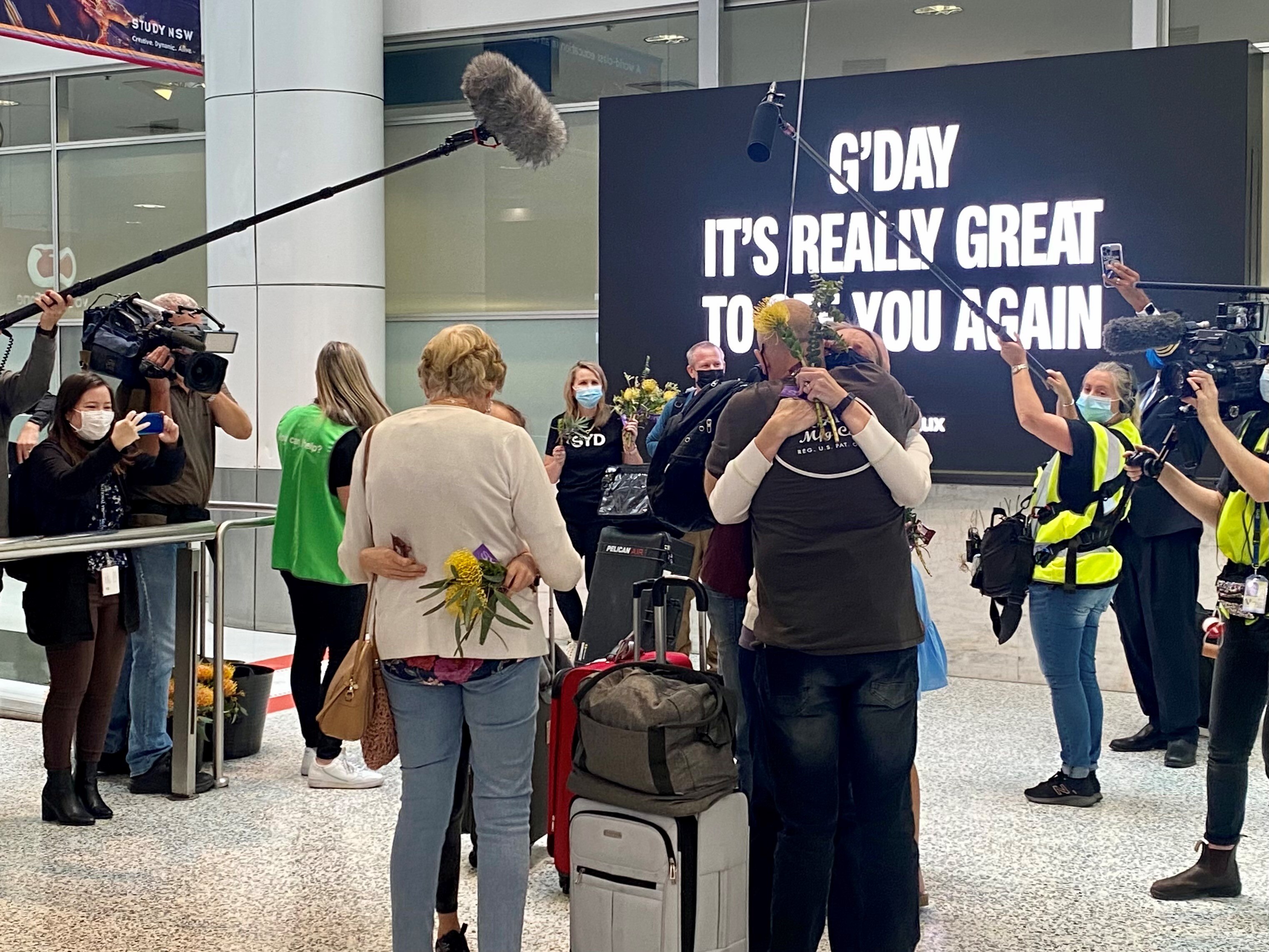Family members embrace oneanother surrounded by cameras and microphones on boom poles. 