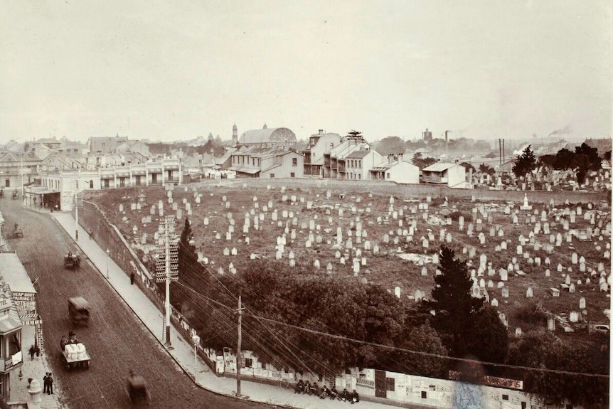 A black and white aerial photo of a cemetery surrounded by houses and a road.