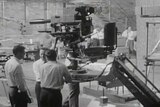 Grainy footage of three men operating a large camera in an ABC studio.
