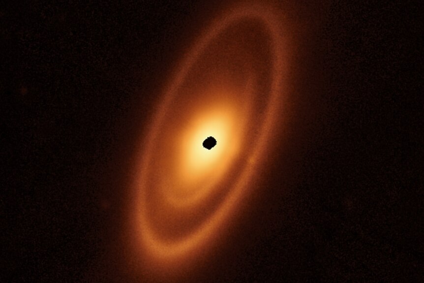 A telescope image of a star, which looks like a black dot in the middle with yellow/orange rings around it.