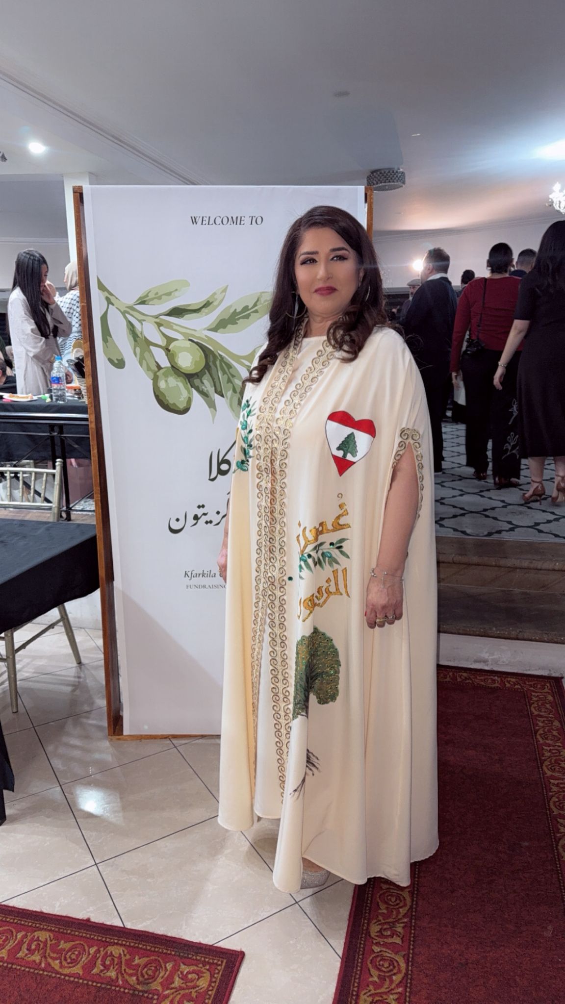 A woman wears a traditional beige Lebanese dress. The Lebanese flag appears on the right hand side.