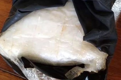 A black bag containing a plastic bag filled with a white substance.