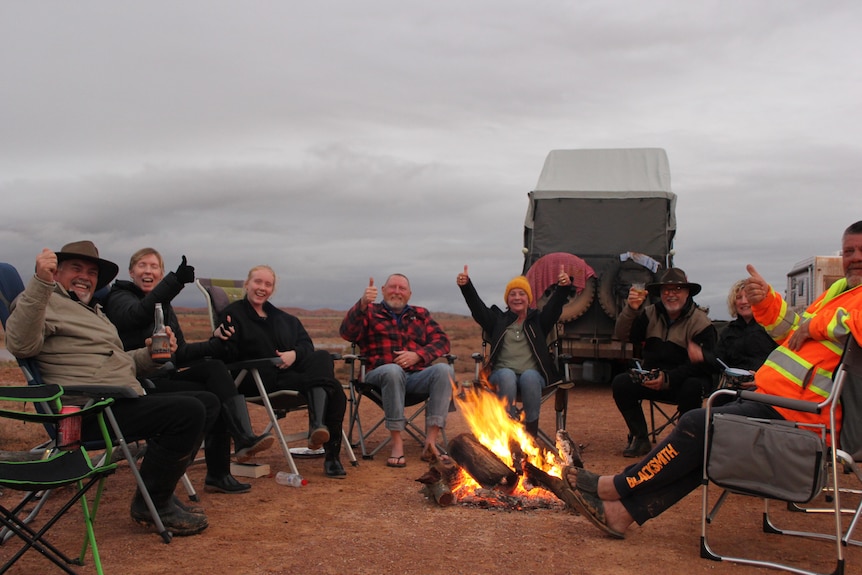 group of people sitting around a bushfire