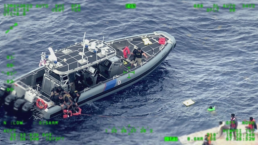 a rescue boat next to a migrant boat at sea in a still image from surveillance aircraft video
