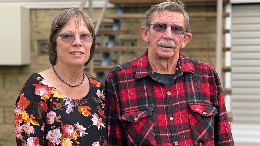 Man wearing red and black check shirt and woman wearing black and orange floral shirt