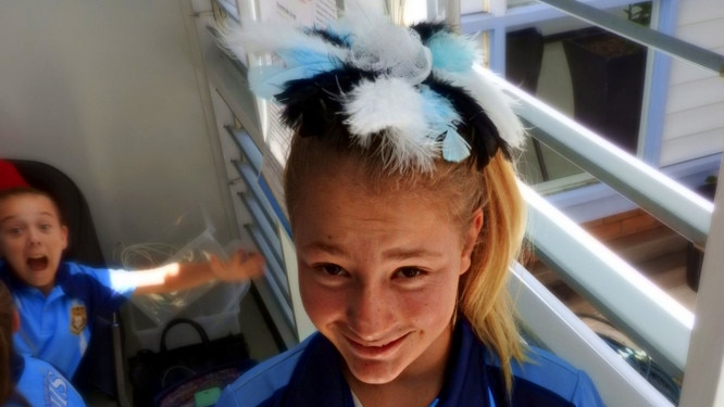 A high school student shows off the fascinator on her head.