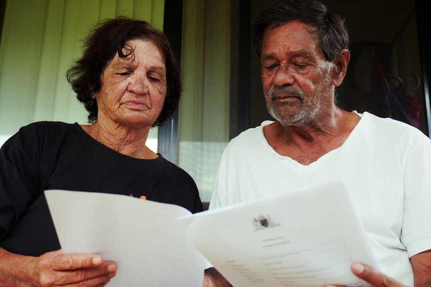 Man and woman sit reading document in front of glass sliding door.