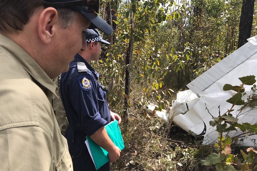 Police officers examine light plane wreckage.