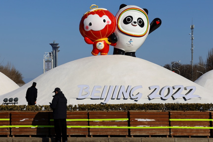 A Chinese lantern child and a panda stand a top a snowy hill.