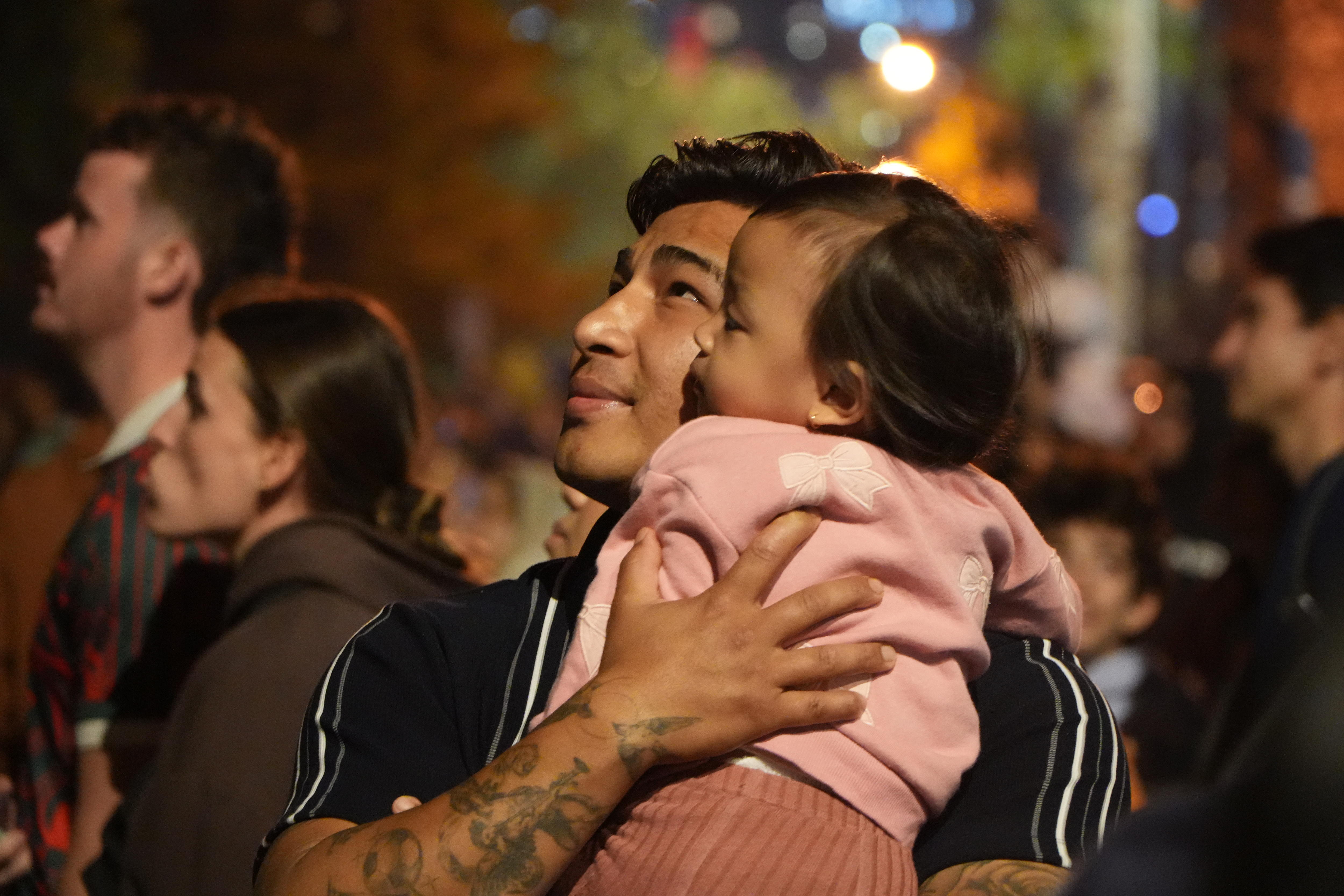 Um homem segura seu filho assistindo aos fogos de artifício.