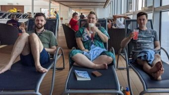 Three people drink cocktails on reclining beds