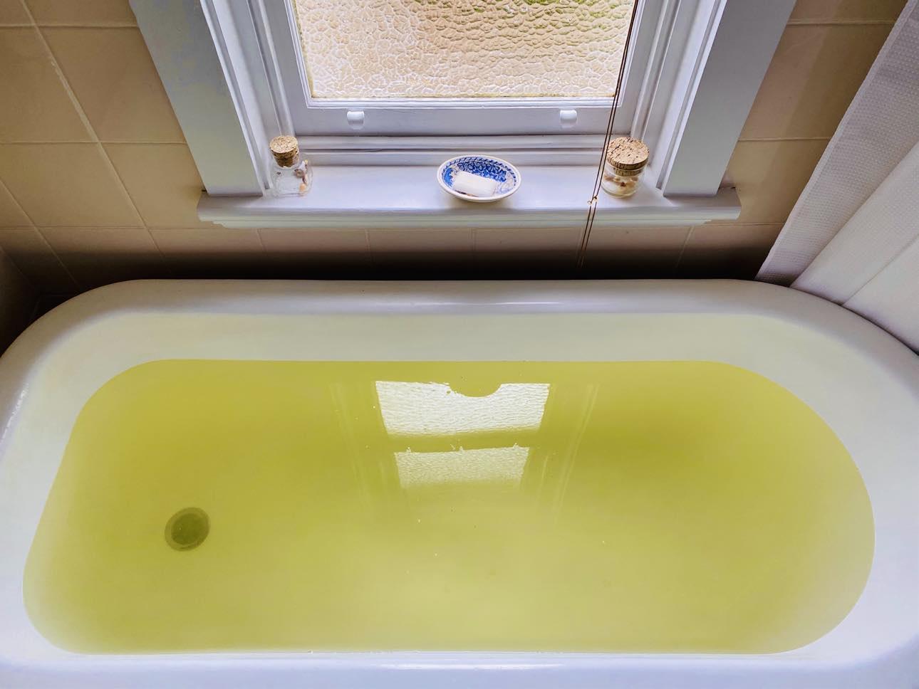 A bathtub filled with water that is yellow