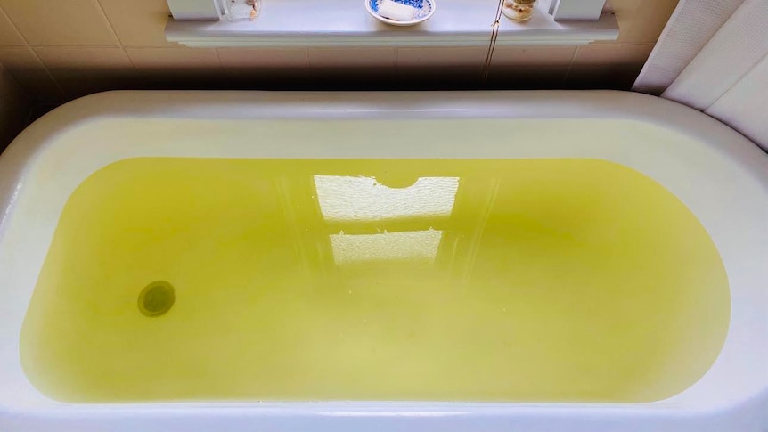 A bathtub filled with water that is yellow